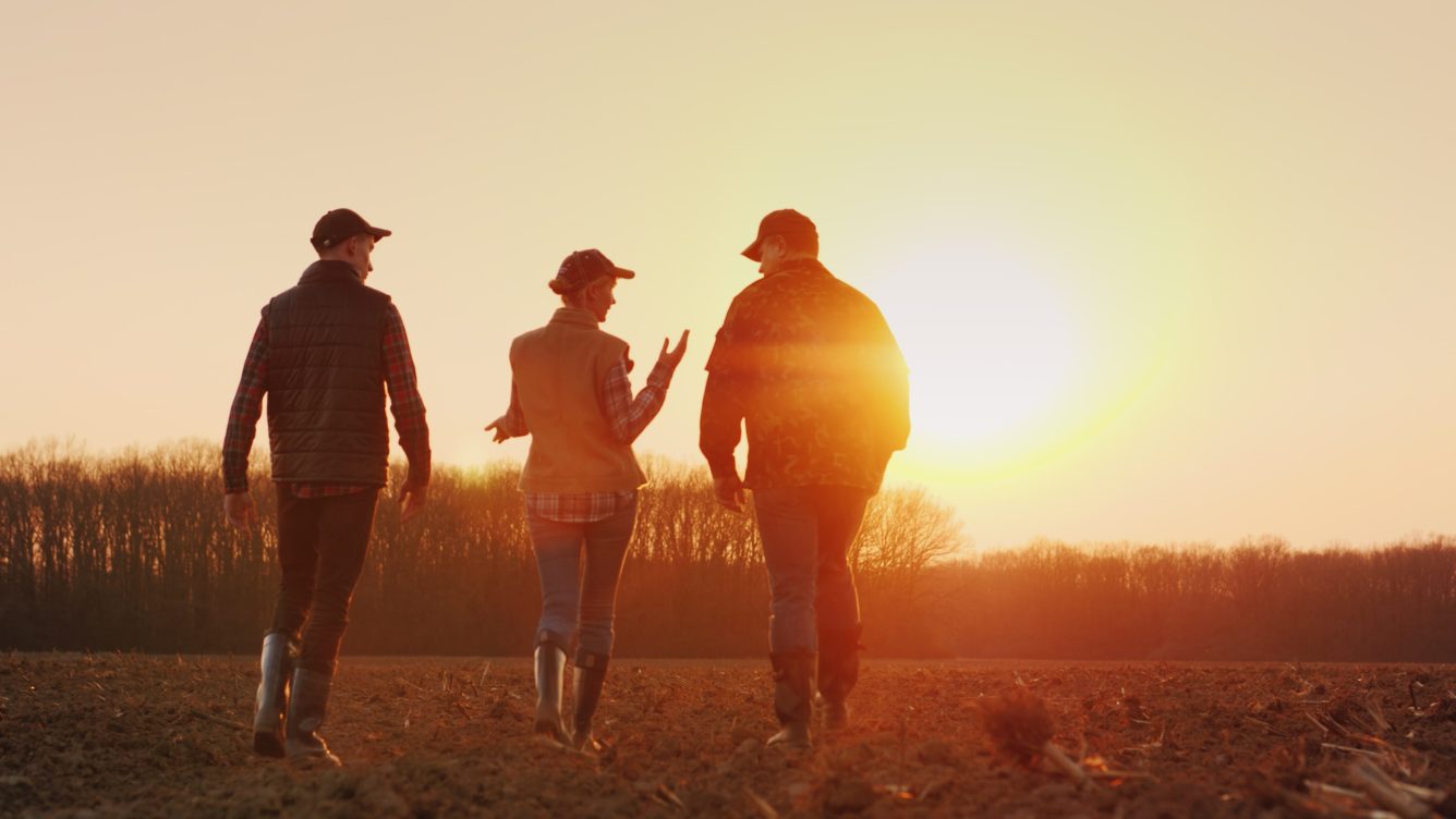 Three farmers walking in the plowed field discussion financial advice