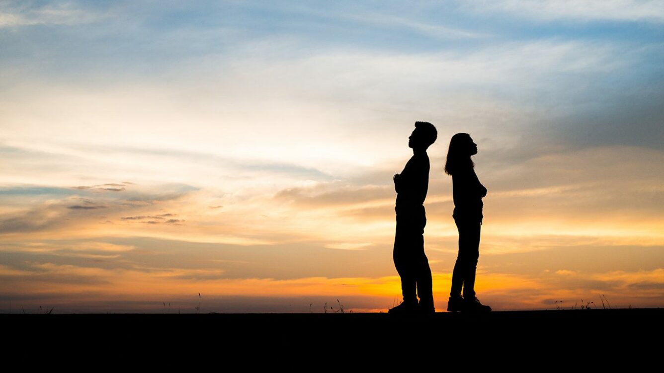 A couple standing back to back after a divorce