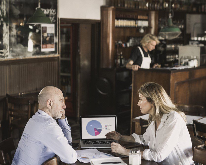 Two people looking at a piechart on a laptop